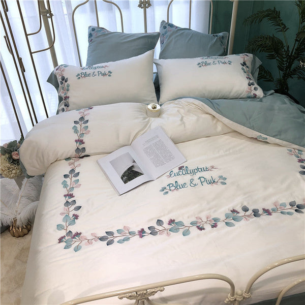 Silky soft embroidered quilt bedding with floral design on a bed.